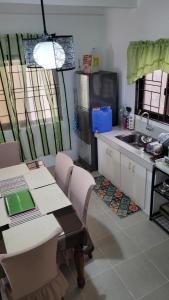 uma cozinha com uma mesa, um lavatório, uma mesa e cadeiras em Camilyn Home Stay em General Trias