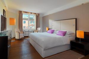 a bedroom with a large white bed with purple pillows at Sheraton Grand Salzburg in Salzburg