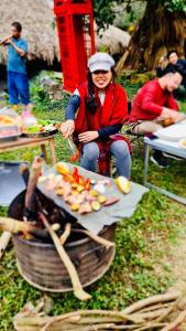 Kobieta gotuje jedzenie na grillu. w obiekcie Mường Retreat- Nghỉ dưỡng xanh trong Bảo tàng Văn hóa Nghệ thuật,Hòa Bình w mieście Quỳnh Lâm