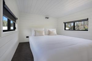 a white bed in a white room with a window at Boydtown Beach Holiday Park in Eden