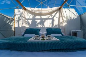 a bed with a blue comforter in a tent at ADAMA Glamping in Chiclana de la Frontera