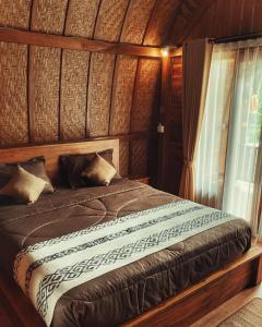 Cama en habitación de madera con ventana en Besakih Homestay & Villa en Besakih