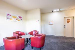 a waiting room with red leather chairs and a table at Nightcap at High Flyer Hotel in Bankstown