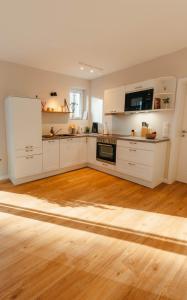 a kitchen with white cabinets and a wooden floor at Fine Stuuv in Ratzeburg