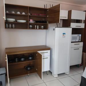 cocina con nevera blanca y armarios de madera en Sea Mar Flat, en Natal