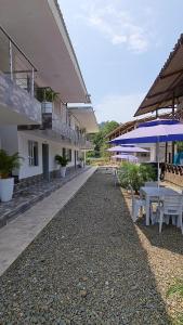 un patio con mesas y sombrillas junto a un edificio en Ecohotel Linda Judith, en Bahía Solano