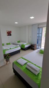 Habitación con 4 camas con sábanas verdes en Ecohotel Linda Judith, en Bahía Solano