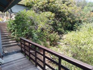 un porche de madera con escaleras y arbustos en Résidence Tamaumia - chambre en Hakamui