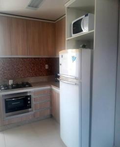 a kitchen with a white refrigerator and a microwave at Apartamento 5 min do Consulado Americano Porto Alegre in Porto Alegre