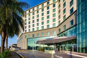 Marriott Panama Hotel - Albrook في مدينة باناما: مبنى كبير أمامه نخلة