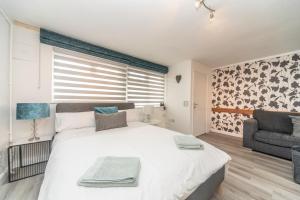 a bedroom with a large white bed and a couch at 10 Boutique Studio Apartment near Tube - quiet location in Little Missenden