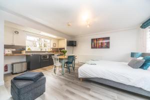 a bedroom with a bed and a table and a kitchen at 10 Boutique Studio Apartment near Tube - quiet location in Little Missenden