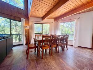 a dining room with a table and chairs and windows at Sublime Cedar Lodge Leura in Leura