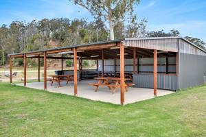 a pavilion with picnic tables in a park at Boydtown Beach Holiday Park in Eden