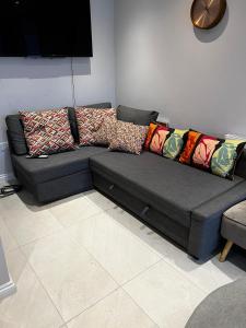 a gray couch with colorful pillows in a living room at 2b Seymour road in Hackbridge