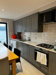 a kitchen with gray cabinets and a table and a table and a dining room at 2b Seymour road in Hackbridge