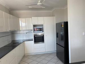 Sea View Full Apartment at Darwin City Heart في داروين: مطبخ فيه دواليب بيضاء وثلاجة سوداء