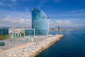 a tall glass building next to a body of water at W Barcelona in Barcelona