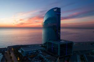 ein hohes Gebäude mit einer Uhr am Meer in der Unterkunft W Barcelona in Barcelona