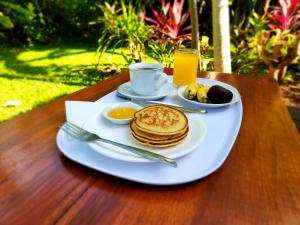 un plato de panqueques y una taza de café y un plato de zumo en Timbis Homestay Bali, en Nusa Dua