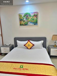 a bedroom with a white bed with a yellow and orange pillow at HANZ Bao Long Riverside Hotel in Ho Chi Minh City