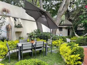 una mesa y sillas con una sombrilla en el jardín en Casa grande en Coyoacán ideal para familias y varios acompañantes, en Ciudad de México