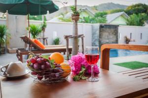 a glass of wine and a bowl of fruit on a table at Happy Eight Resort in Nai Harn Beach