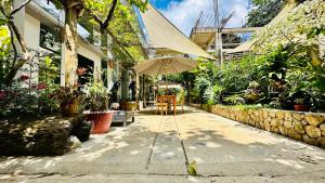 a patio with an umbrella and chairs and plants at Hidden of Cailan Inn in El Nido