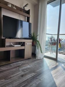 een woonkamer met een televisie en een groot raam bij Dpto acogedor con terraza privada in Lima +29 foto's