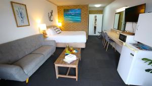 a hotel room with a bed and a couch at Tweed Harbour Motor Inn in Tweed Heads