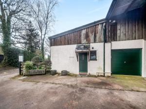 un antiguo edificio blanco con un garaje verde en The Garden Lodge, en Broadhembury