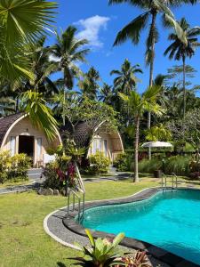 un complejo con piscina y palmeras en Mulia Manise The Bahari Villas Bali en Pacung
