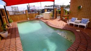 a small swimming pool on a patio with an umbrella at Tweed Harbour Motor Inn in Tweed Heads