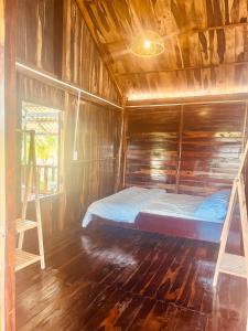 ein Schlafzimmer mit einem Bett in einer Holzhütte in der Unterkunft Thông Garden - Lộc Đức in Bảo Lộc