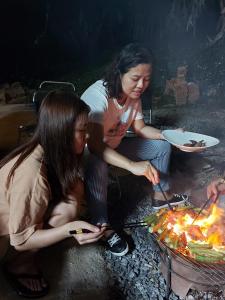 Eine Gruppe von Frauen, die Essen über dem Feuer kochen in der Unterkunft Thông Garden - Lộc Đức in Bảo Lộc