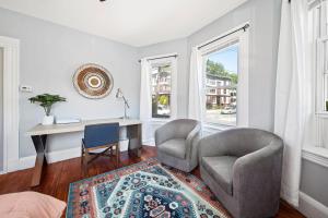 a living room with a desk and two chairs and a table at Cozy Up in 5BR Apt Near Charming Oak Square in Boston