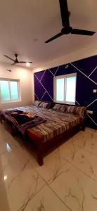 a large bed in a room with purple walls at ROYAL GRAND Homestay & Resort in Vālpārai