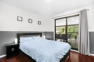 a bedroom with a bed and a large window at Baileys Retreat in Leura