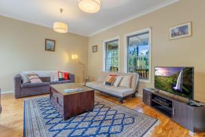 ein Wohnzimmer mit einem Sofa und einem TV in der Unterkunft Scenic Cottage in Katoomba