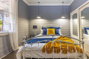 Schlafzimmer mit einem Bett mit blauen und gelben Kissen in der Unterkunft Bluebell Cottage in Katoomba