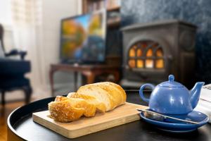ein Laib Brot auf einem Schneidebrett neben einer Teekanne in der Unterkunft Bluebell Cottage in Katoomba + 20 Fotos