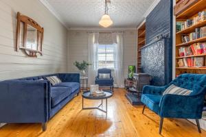 ein Wohnzimmer mit zwei blauen Sofas und einem Tisch in der Unterkunft Bluebell Cottage in Katoomba