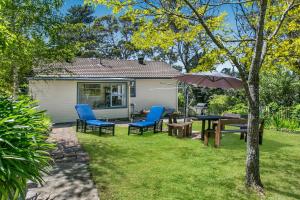 a patio with a table and chairs and an umbrella at Lavender Cottage in Leura