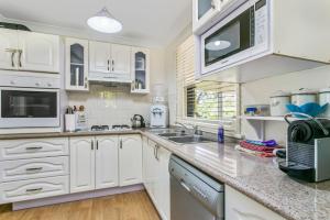 a kitchen with white cabinets and white appliances at Lavender Cottage in Leura