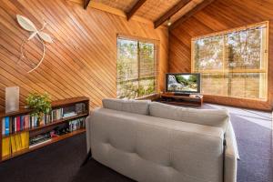 a living room with a couch and a tv at Grey Gum Lodge in Woodford