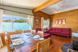 a dining room with a table and a red couch at Keira Cottage in Katoomba
