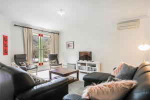 Una sala de estar con un sofá y sillas y una mesa. en Minnehaha, en Katoomba