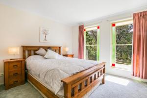 1 Schlafzimmer mit einem Holzbett und 2 Fenstern in der Unterkunft Minnehaha in Katoomba
