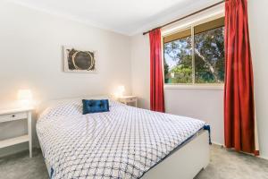 Un dormitorio con una cama y una ventana con cortinas rojas. en Minnehaha, en Katoomba