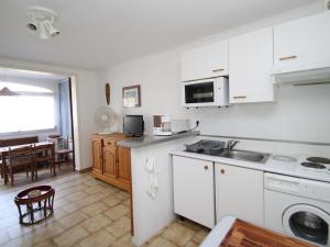 uma cozinha com armários brancos, um lavatório e uma mesa em Appartement Argelès-sur-Mer, 2 pièces, 4 personnes - FR-1-309-255 em Argelès-sur-Mer